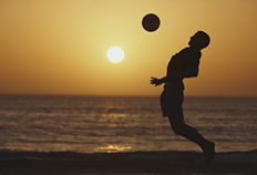 Silueta de futbolista atardeciendo en la playa.