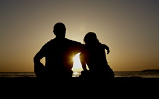 Pareja mirando el atardecer sobre el mar.