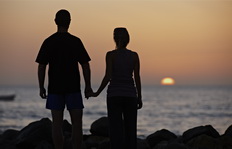 Pareja mirando la puesta de Sol en el mar, derecha.